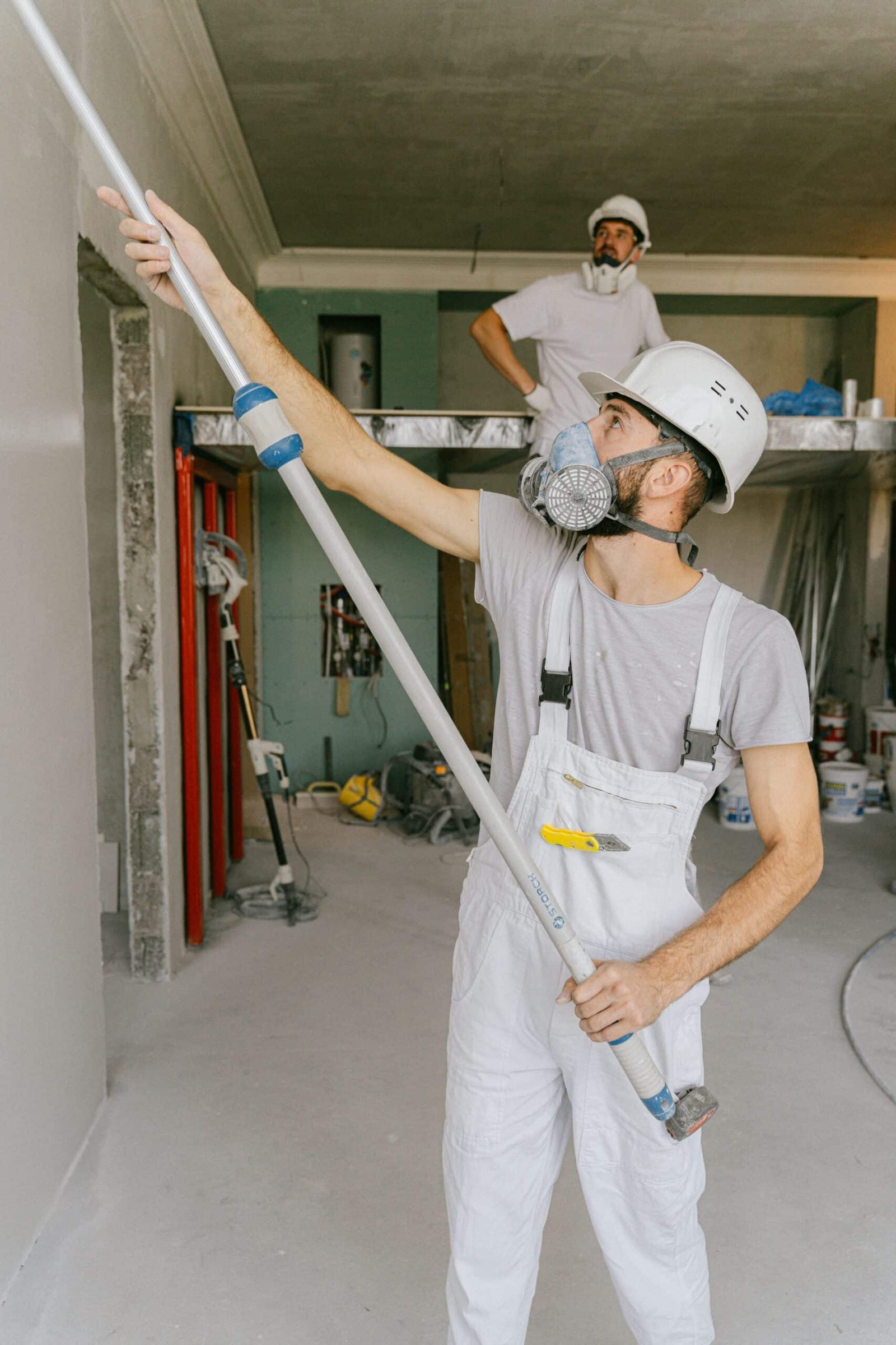 Contractors in coveralls and hard hats finishing wall construction on a commercial jobsite